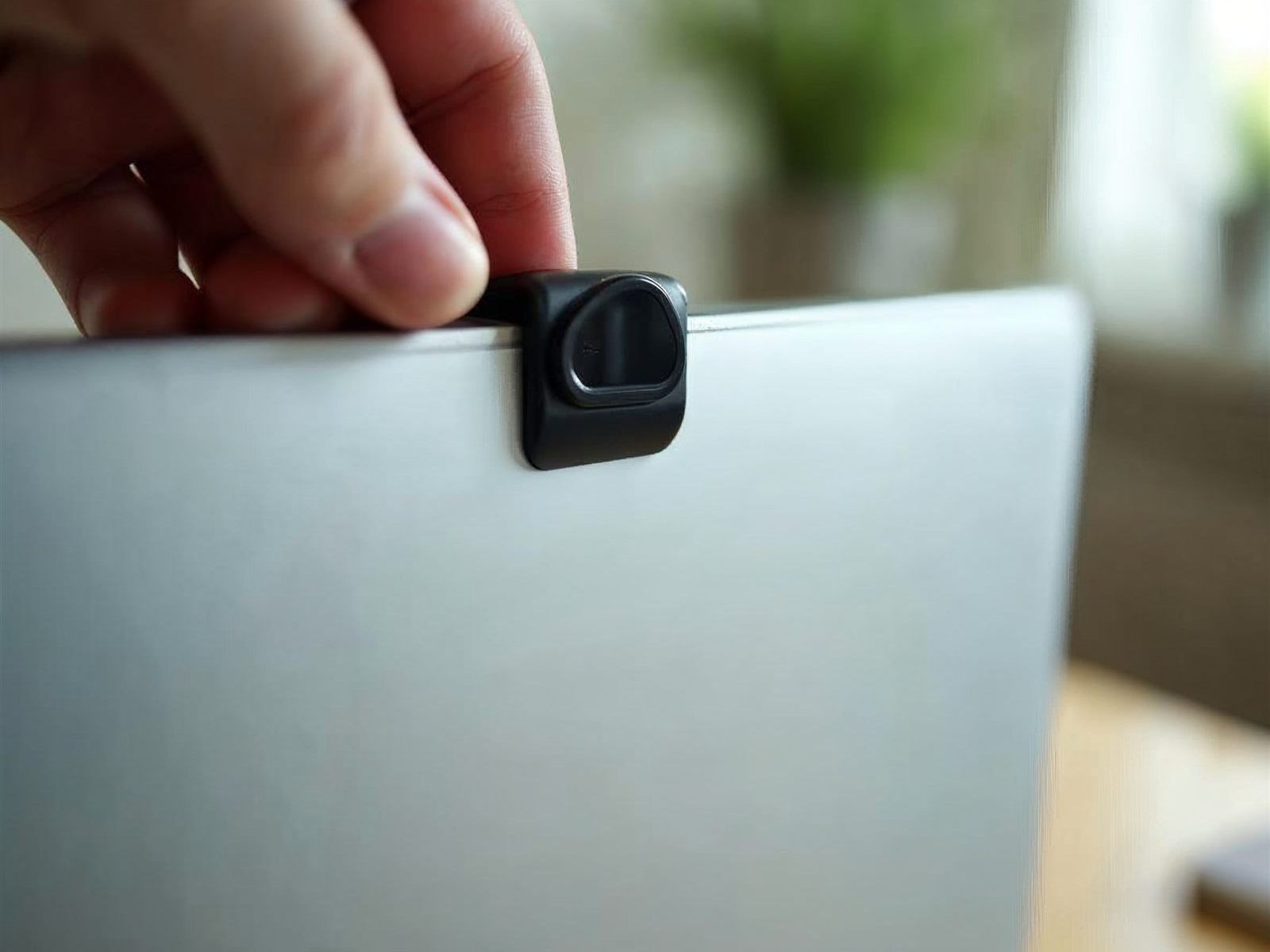 Mano colocando una tapa de privacidad sobre la webcam de un portátil
